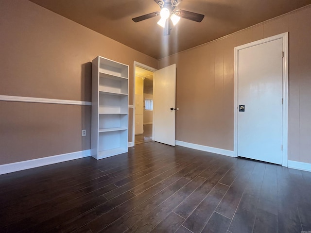 unfurnished bedroom with dark wood-type flooring, a ceiling fan, and baseboards