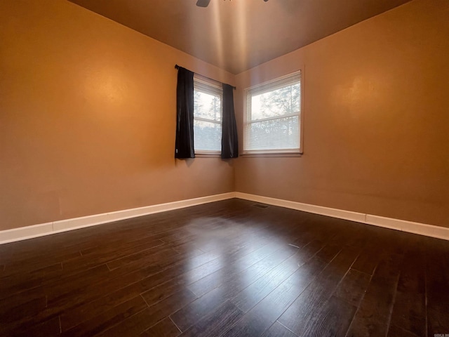 spare room with baseboards and dark wood-type flooring