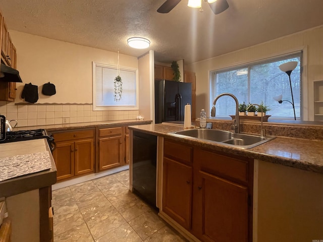 kitchen featuring tasteful backsplash, brown cabinetry, a textured ceiling, black appliances, and a sink