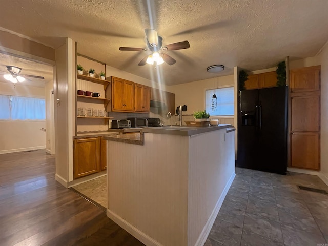 kitchen featuring ceiling fan, black fridge, brown cabinets, open shelves, and dark countertops