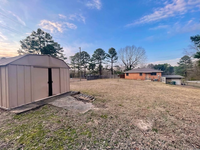 view of yard featuring a storage unit, an outdoor structure, and fence