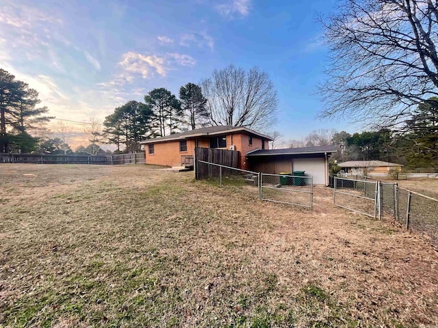 rear view of property featuring a garage, a yard, fence, and a gate