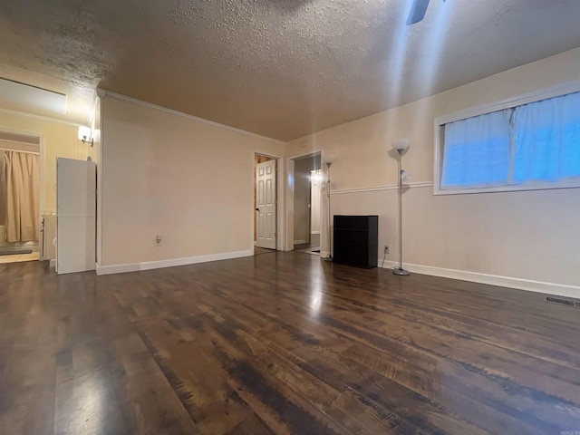 unfurnished living room with baseboards, visible vents, dark wood finished floors, and a textured ceiling