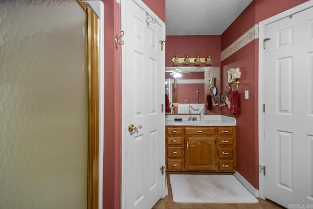 bathroom with a shower with door, baseboards, a textured ceiling, and vanity