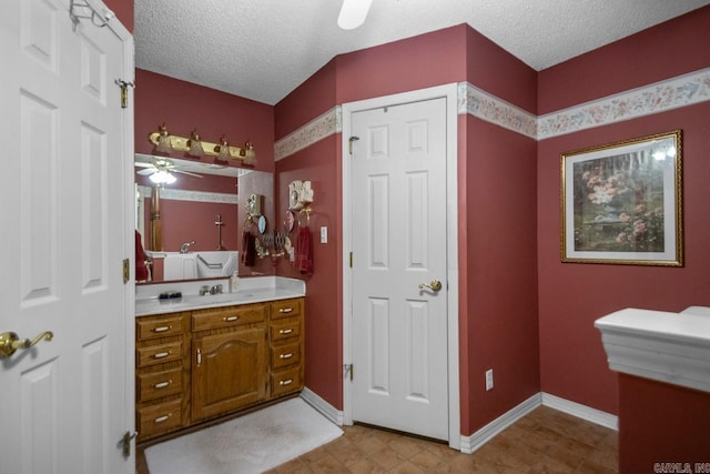 bathroom with baseboards, ceiling fan, a textured ceiling, and vanity