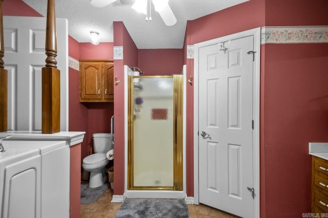 bathroom featuring a textured ceiling, toilet, vanity, independent washer and dryer, and a shower stall