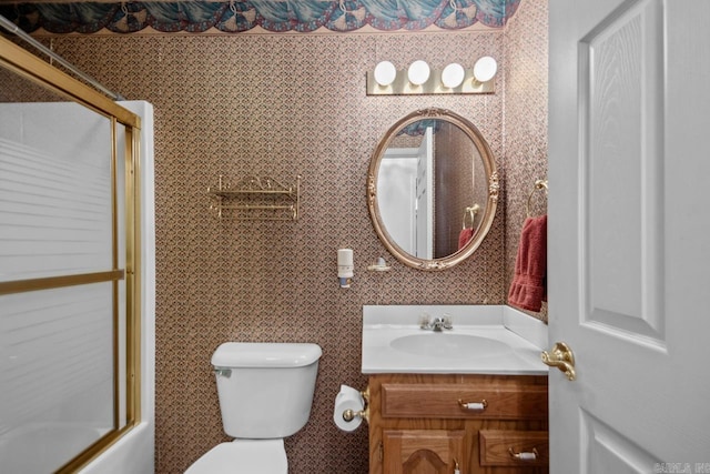 bathroom with enclosed tub / shower combo, vanity, toilet, and wallpapered walls