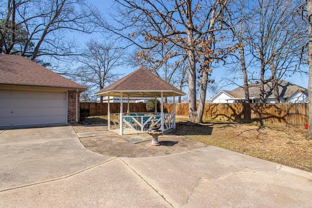 view of yard with a garage, a fenced backyard, and a gazebo