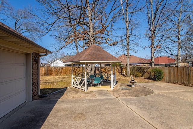 view of patio / terrace with a garage, a fenced backyard, and a gazebo