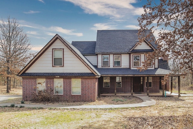 view of front of house featuring a shingled roof, a porch, and brick siding