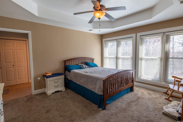 carpeted bedroom with a raised ceiling, visible vents, baseboards, and multiple windows