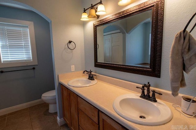 full bathroom featuring double vanity, tile patterned flooring, a sink, and toilet