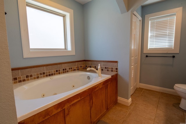 full bathroom featuring a whirlpool tub, baseboards, toilet, and tile patterned floors