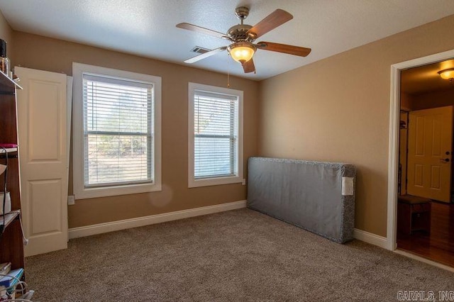 unfurnished room featuring carpet floors, baseboards, visible vents, and a ceiling fan