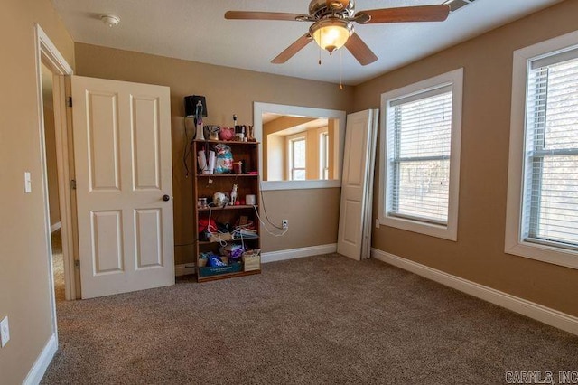 unfurnished bedroom with a ceiling fan, multiple windows, baseboards, and carpet flooring