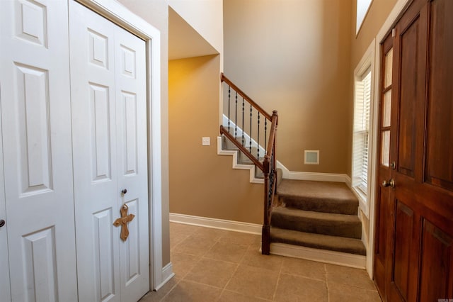 entryway with light tile patterned floors, stairway, and baseboards