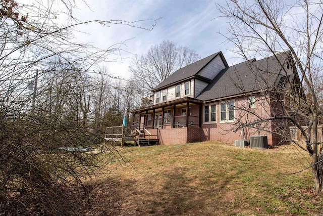 view of side of property featuring roof with shingles, brick siding, a lawn, and cooling unit