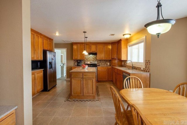 kitchen with light tile patterned floors, brown cabinets, backsplash, black appliances, and a sink