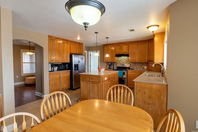 kitchen featuring tasteful backsplash, visible vents, arched walkways, appliances with stainless steel finishes, and a sink