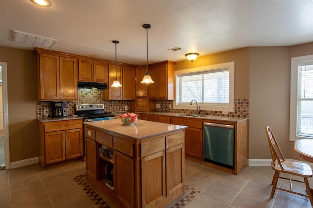 kitchen featuring under cabinet range hood, stainless steel appliances, a sink, visible vents, and brown cabinetry