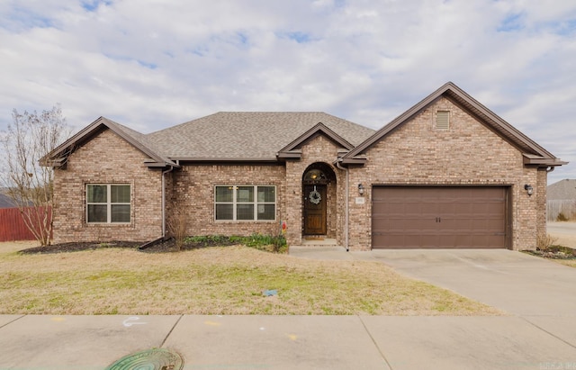 view of front facade featuring driveway, a garage, fence, a front lawn, and brick siding