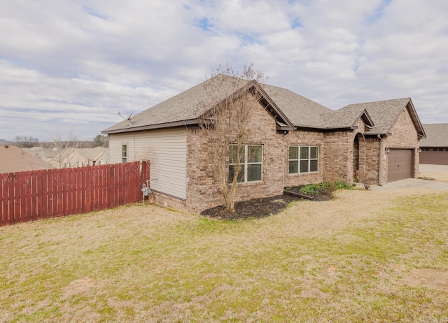 view of property exterior featuring an attached garage, brick siding, fence, a yard, and roof with shingles