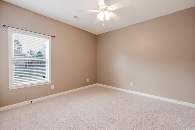 carpeted empty room with a ceiling fan, visible vents, and baseboards