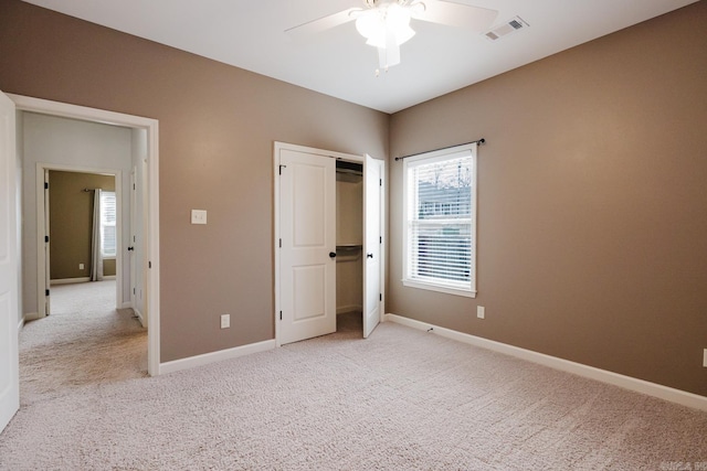 unfurnished bedroom featuring baseboards, ceiling fan, visible vents, and light colored carpet