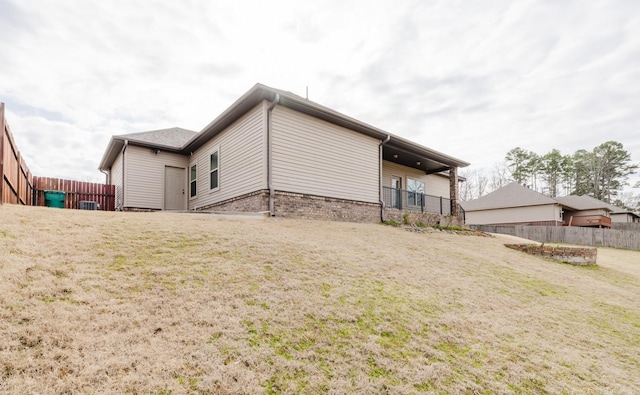 rear view of house with a yard, brick siding, and fence