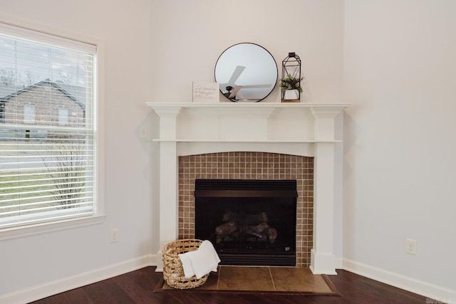 room details featuring a tile fireplace, wood finished floors, and baseboards