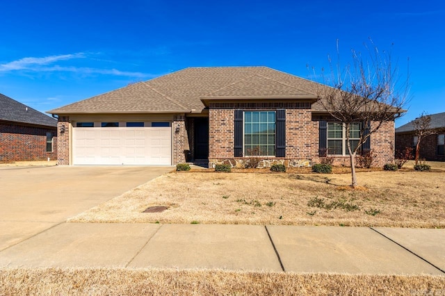 view of front facade with a garage, driveway, brick siding, and roof with shingles