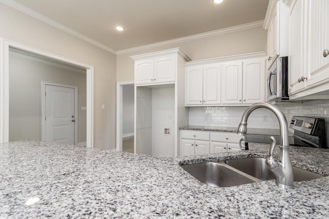 kitchen with light stone countertops, white cabinetry, stainless steel microwave, and a sink