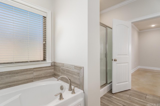 bathroom with wood finished floors, baseboards, ornamental molding, a bath, and a stall shower