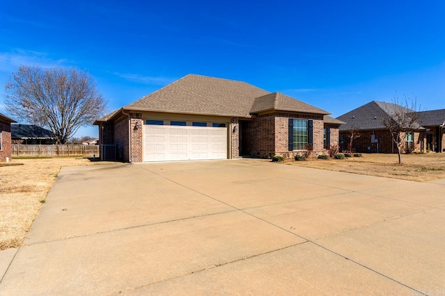 view of front facade featuring concrete driveway, brick siding, fence, and an attached garage