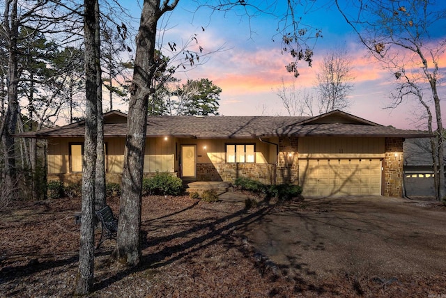 view of front facade with a garage, stone siding, and driveway