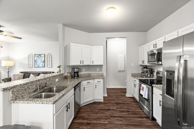 kitchen featuring stainless steel appliances, dark wood-type flooring, a peninsula, a sink, and white cabinets