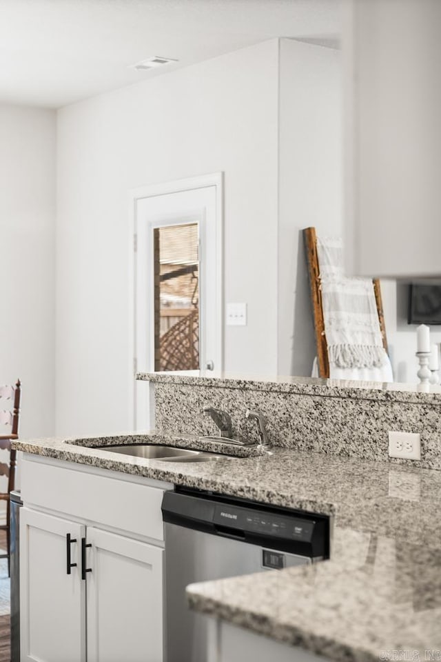 kitchen featuring light stone counters, a sink, visible vents, white cabinets, and dishwasher