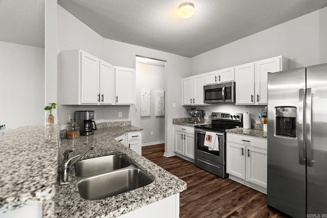 kitchen with light stone counters, dark wood-style flooring, appliances with stainless steel finishes, white cabinets, and a textured ceiling