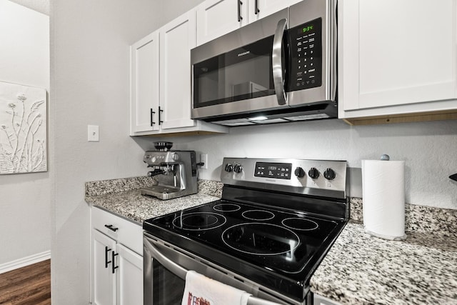 kitchen featuring stainless steel appliances, baseboards, white cabinets, light stone countertops, and dark wood finished floors