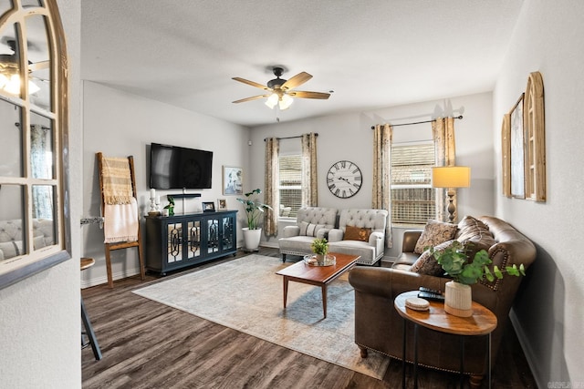 living area featuring a ceiling fan, dark wood finished floors, a textured ceiling, and baseboards