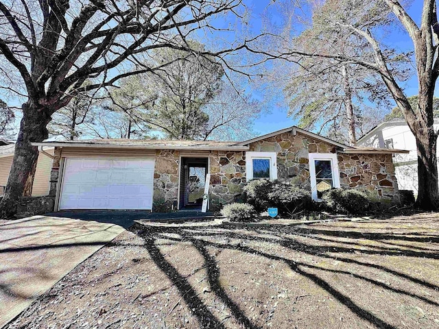 view of front of home with a garage, driveway, and stone siding