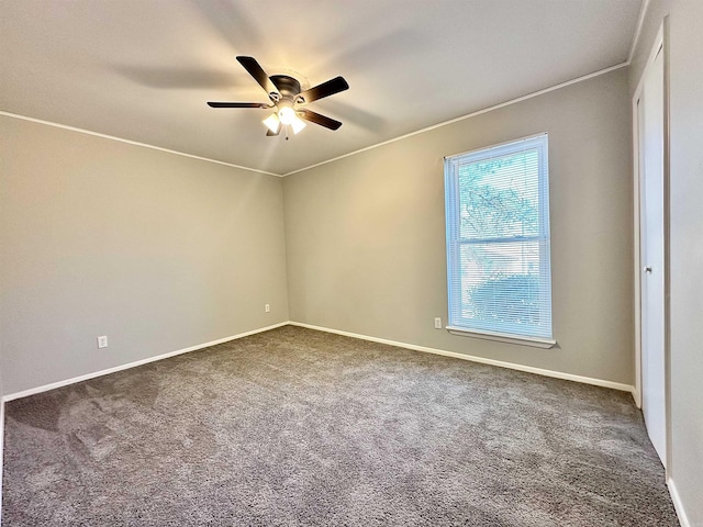 empty room with crown molding, carpet floors, a ceiling fan, and baseboards