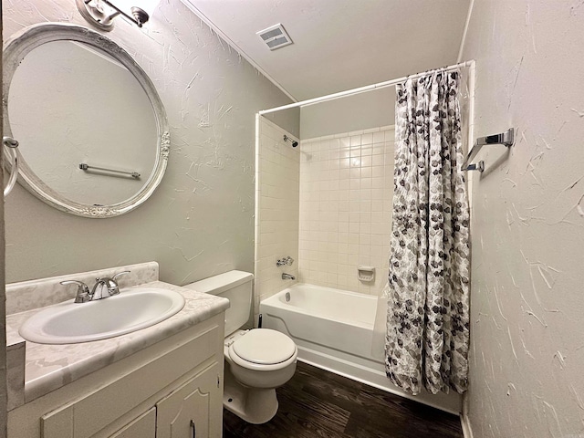 bathroom with visible vents, a textured wall, toilet, vanity, and wood finished floors