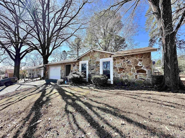 ranch-style house featuring stone siding, concrete driveway, and an attached garage