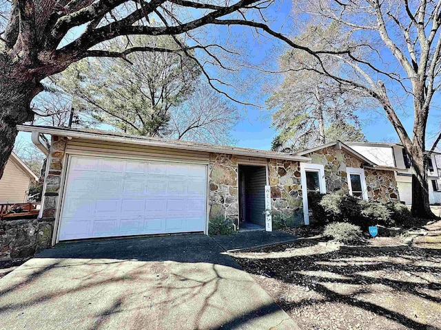 view of front facade featuring a garage, stone siding, and driveway