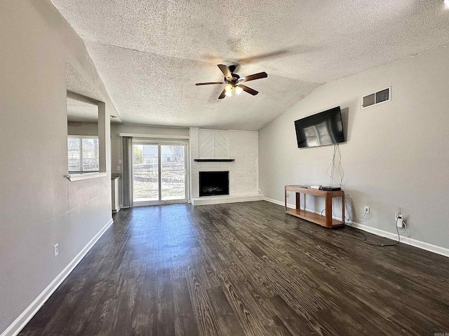 unfurnished living room featuring baseboards, visible vents, lofted ceiling, dark wood-style flooring, and a fireplace