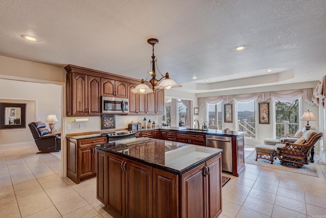 kitchen with a kitchen island, a peninsula, a notable chandelier, stainless steel appliances, and a sink