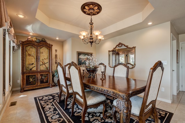 dining room featuring light tile patterned floors, a chandelier, visible vents, baseboards, and a tray ceiling