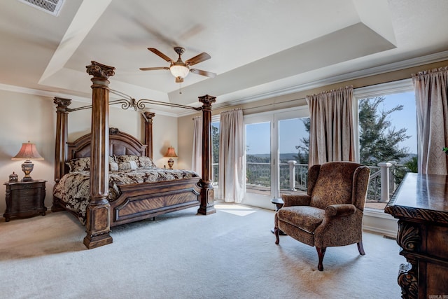 carpeted bedroom with a tray ceiling, access to outside, visible vents, and multiple windows