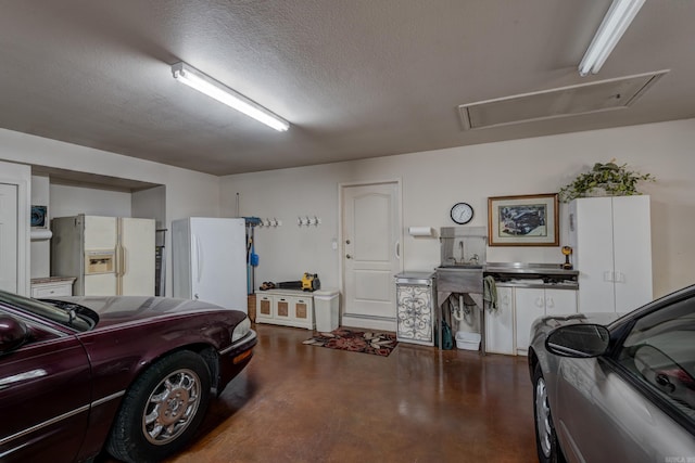 garage with freestanding refrigerator and white refrigerator with ice dispenser